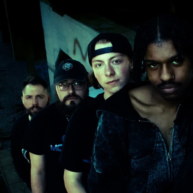 Cold Promise band portrait, photographed together in a dark graffiti-covered space